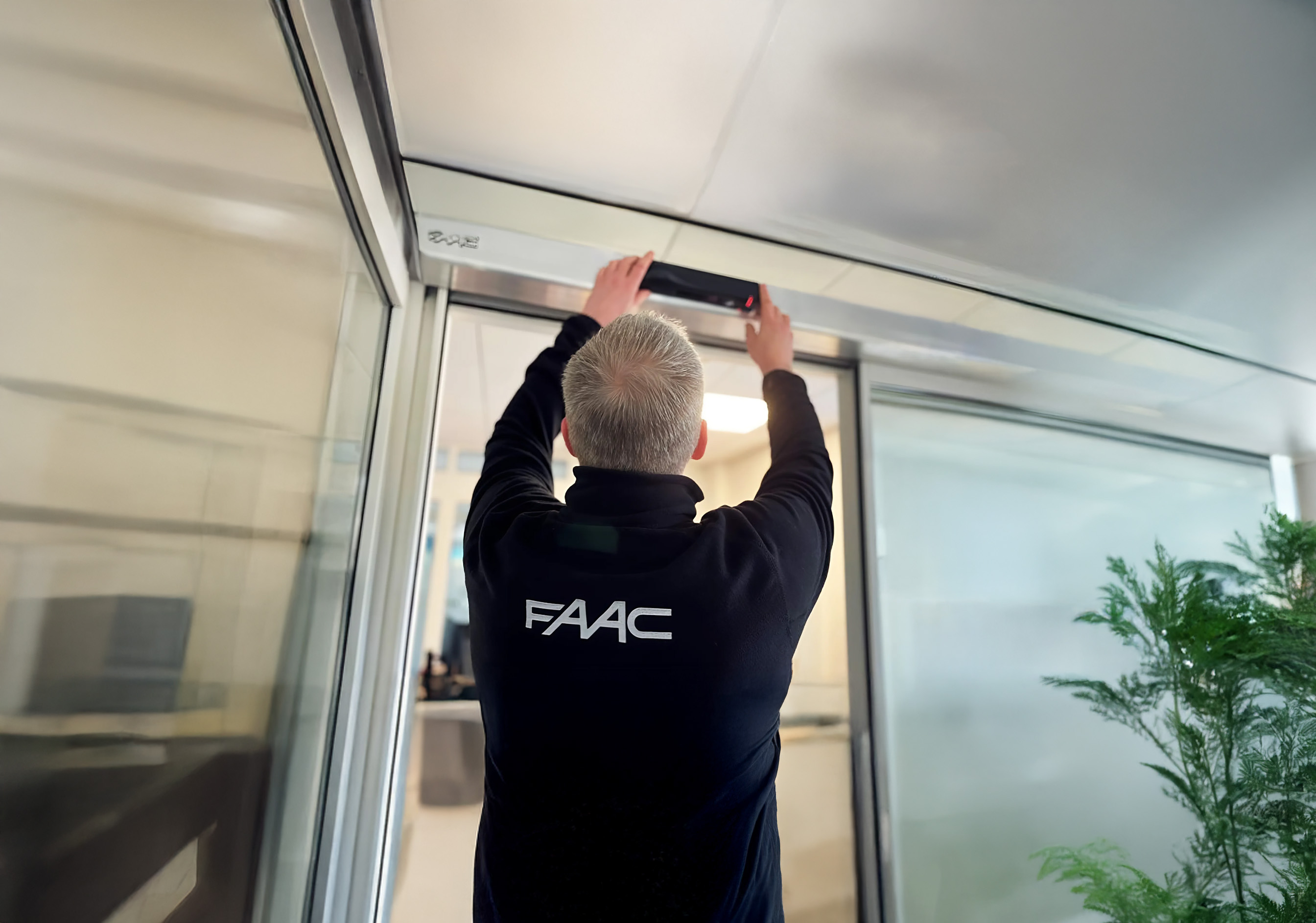 Technicien FAAC intervenant sur une porte automatique piétonne