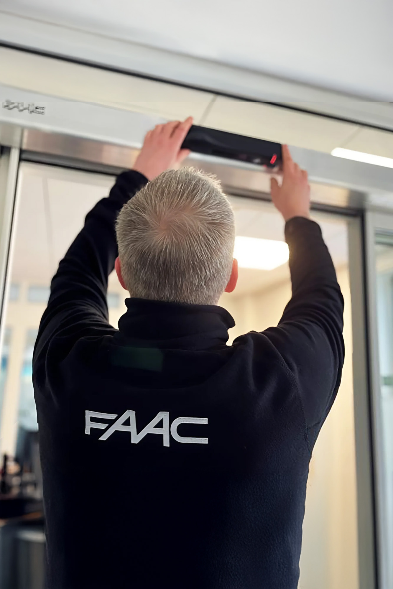 Technicien FAAC intervenant sur une porte automatique piétonne