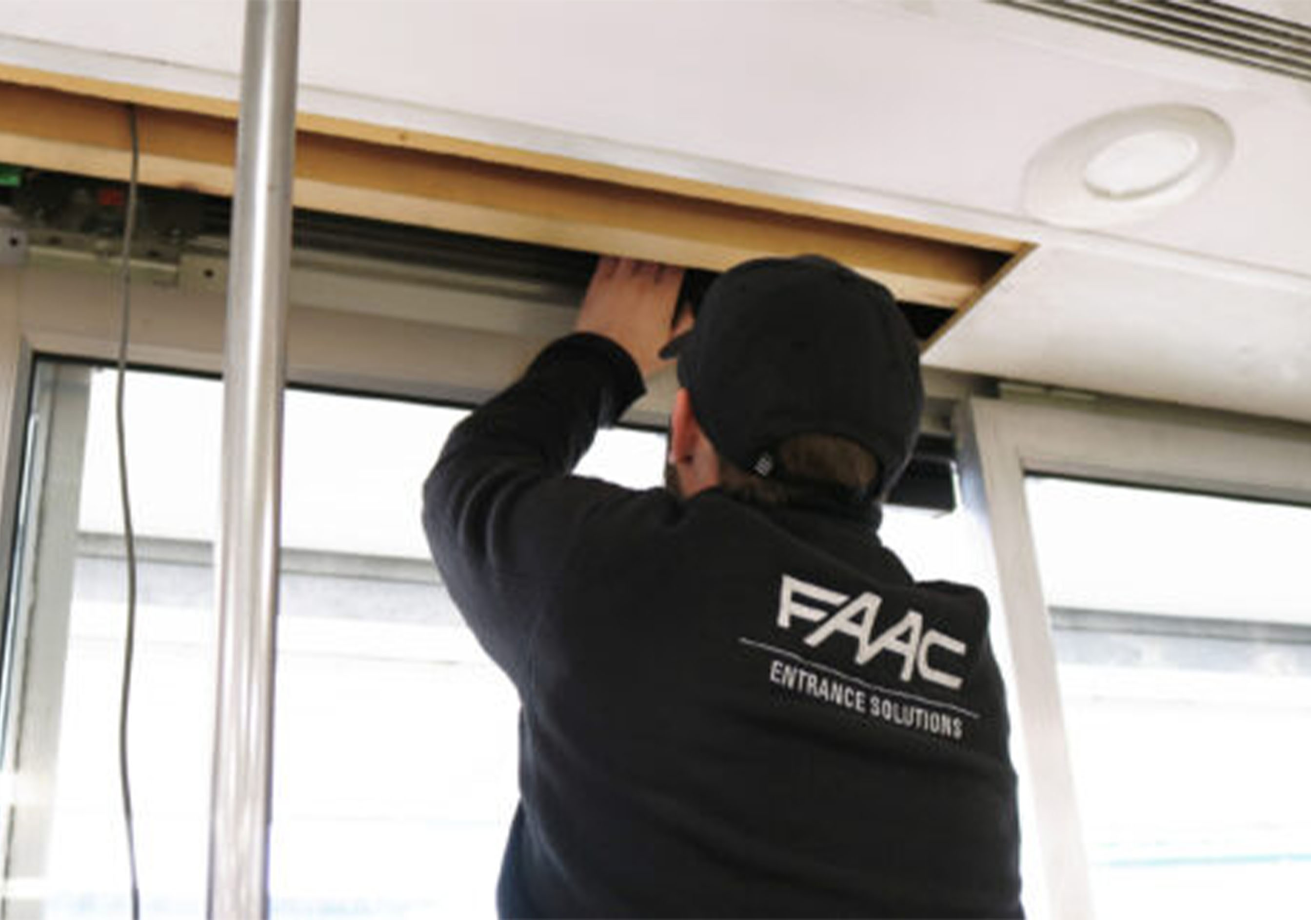 Technicien FAAC effectuant la maintenance de l'opérateur d'une porte automatique coulissante